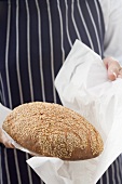 Woman wrapping a loaf of oat bread in paper
