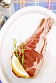 Raw lamb chop on a plate, rosemary, lemon