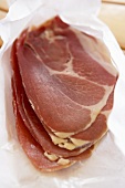Several slices of Parma ham on paper