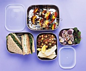 Salads, vegetable kebabs and sandwiches in lunch boxes