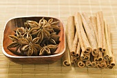 Star anise in wooden bowl, cinnamon sticks beside it