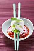 Vietnamese spring roll on chopsticks over chili sauce