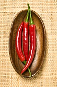 Three chili peppers in wooden bowl