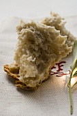 Pieces of white bread on linen cloth beside olive sprig