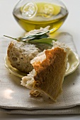 Pieces of white bread on plate with olive sprig, olive oil