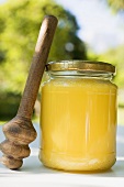 Jar of honey with honey dipper on table in the open air