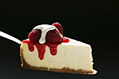 Slice of cheesecake with raspberries & cream on cake server