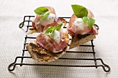 Three crostini with Parma ham, mozzarella and basil