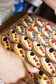Chef holding tray of assorted berry tartlets