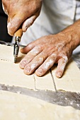 Cutting pasta dough into strips with pastry wheel