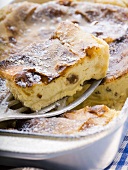 Curd cheese strudel in baking tin with piece on server