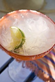 Margarita with wedge of lime in orange glass