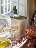 White wine bottle in ice bucket, wine glasses, lobster, lemon