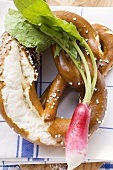 Soft pretzels and radish on tea towel (close-up)