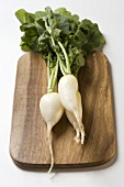 White icicle radishes with leaves on chopping board