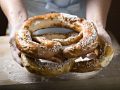 Hands holding two large soft pretzels