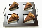 Four pieces of chocolate tart with almonds on tray