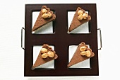 Four pieces of chocolate tart with almonds on tray