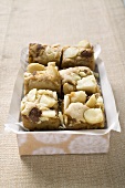 Small pieces of chocolate slice with macadamia nuts in box
