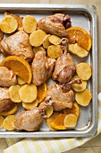 Roast chicken pieces with oranges on baking tray