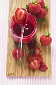 Jar of strawberry jam & fresh strawberries on chopping board