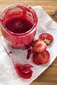 Strawberry jam and fresh strawberries on paper