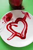 Heart drawn in strawberry jam on plate