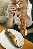 Woman eating pretzel & Steckerlfisch (skewered fish), Oktoberfest
