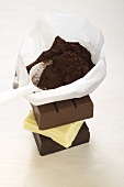 Cocoa powder in bag with scoop on pieces of chocolate