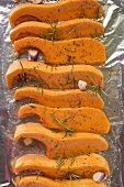 Pumpkin slices with rosemary and garlic on aluminium foil