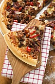 Mince and onion pizza, partly sliced