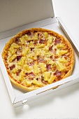 Pizza Hawaii mit Schinken und Ananas im Pizzakarton