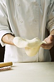 Shaping pizza dough by hand (stretching)