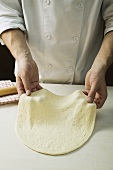 Shaping pizza dough by hand (stretching)