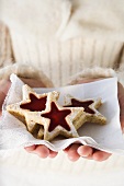 Hands holding jam biscuits on napkin