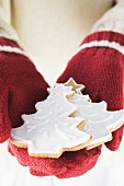 Hands in woollen gloves holding fir tree biscuits
