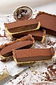 Rectangular chocolate tart with cocoa powder, partly sliced