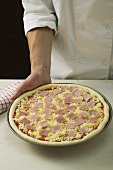 Topping a pizza with ham