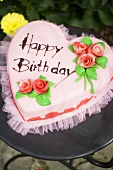 Pink heart-shaped birthday cake on garden table
