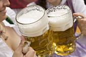 Hände stossen mit zwei Mass Bier an (München, Oktoberfest)