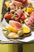 Crostini with raw ham, peppers and giant capers