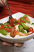 Woman eating tomatoes with mozzarella and basil