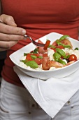 Woman eating tomatoes with mozzarella and basil