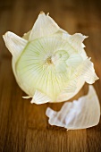 Onion, partly peeled, on wooden background