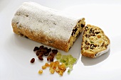 Stollen with icing sugar, a slice cut, and ingredients
