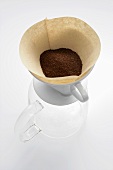 Ground coffee in filter on glass coffee pot
