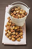Mixed nuts to nibble in and beside white bucket