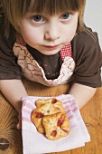 Child holding freshly-baked puff pastries on cloth