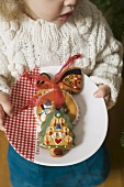 Small girl holding plate of gingerbread tree ornaments