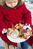 Small girl holding plate of baked tree ornaments